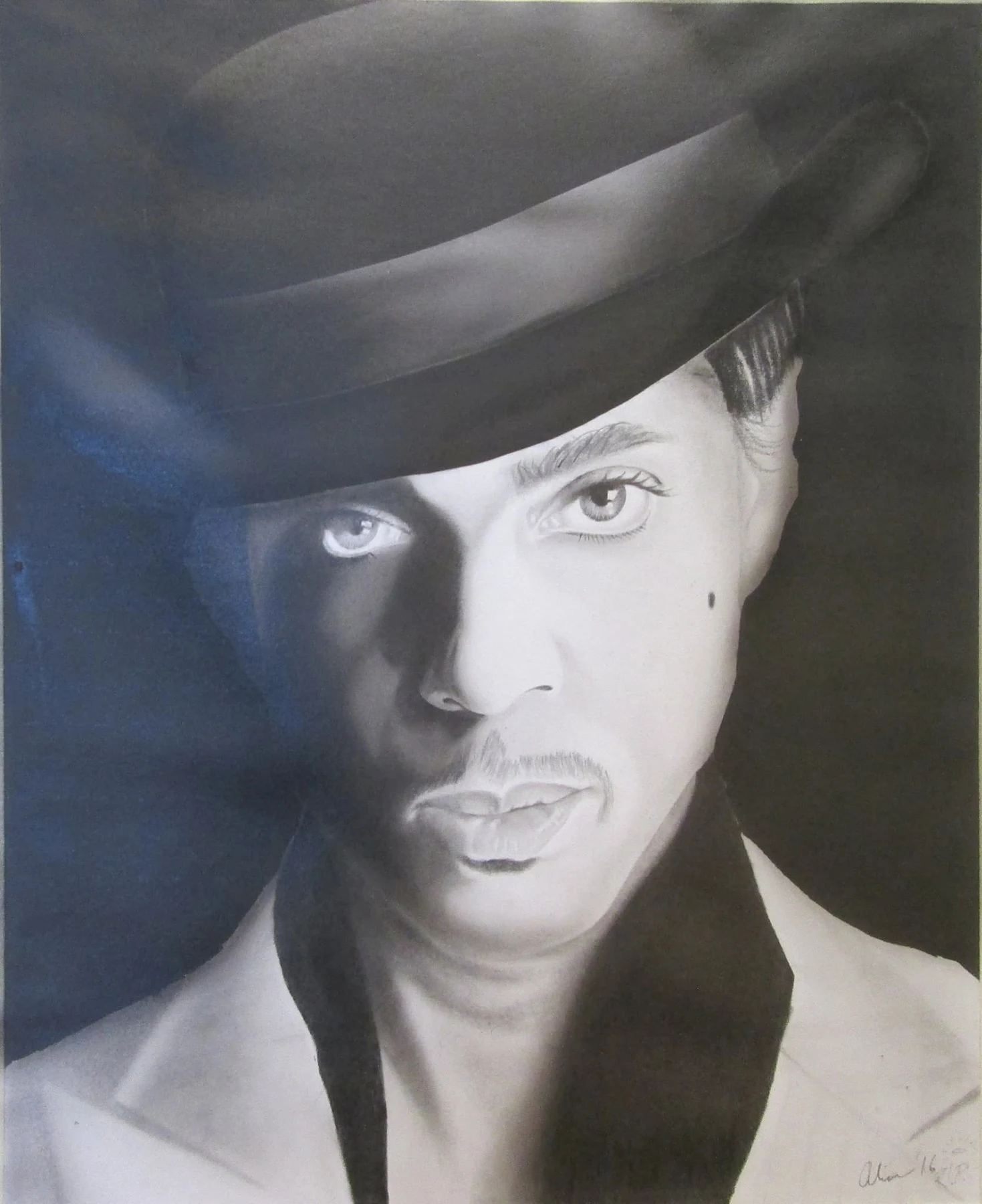 Monochrome portrait of Prince looking forward beneath a dark fedora